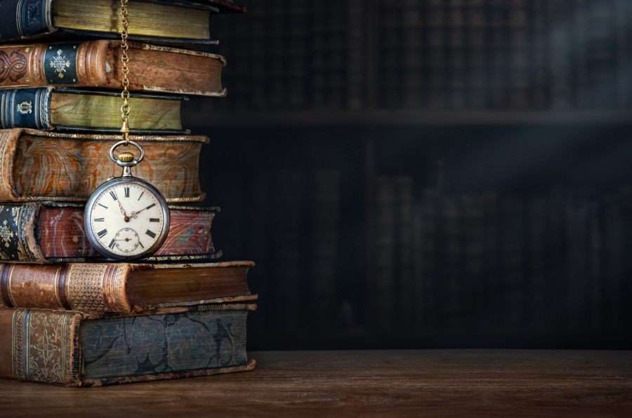Old clock hanging on a chain on the background of old books.  lock as a symbol of time a books are a symbol of knowledge.. Concept on the theme of history, nostalgia, culture.